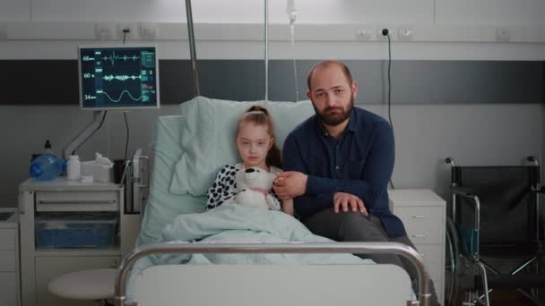 Retrato de pai triste segurando as mãos da criança doente olhando para a câmera durante a consulta médica - Filmagem, Vídeo