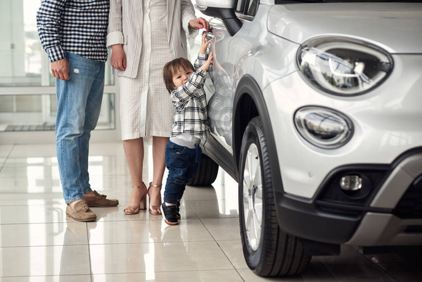 The manager helps the young family choose the most comfortable car for the city. - Valokuva, kuva