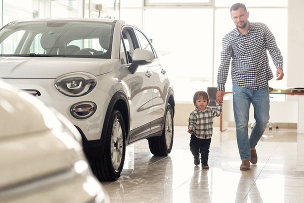 Father and son walk around the big car show and consider new car models. - Φωτογραφία, εικόνα