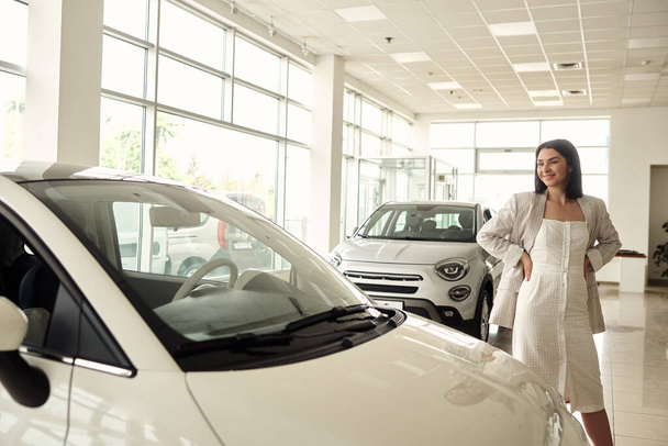 A girl in a car dealership buys a small city car. - Foto, imagen