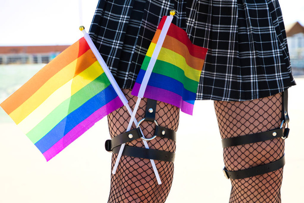girl's leg detail with fishnet stockings and leather garters on which you can see two gay pride flags intertwined with each other. Concept gay lesbian freedom and rights. - Fotografie, Obrázek