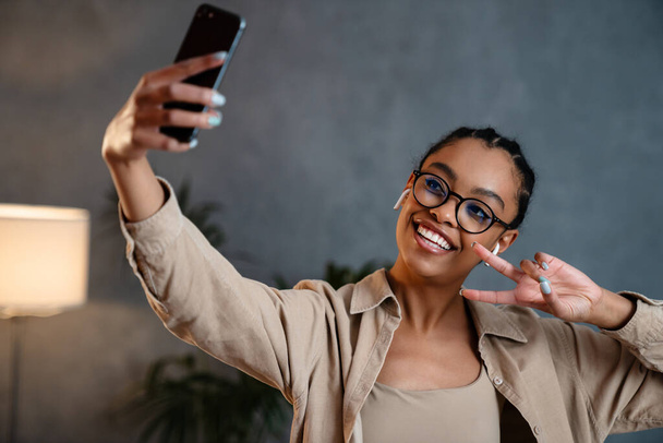 Cheerful african business woman taking a selfie while standing in the office - Fotografie, Obrázek