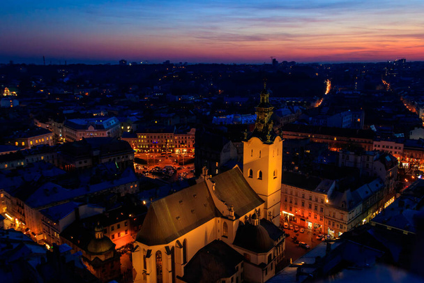 Vista aérea nocturna de la catedral latina iluminada y la plaza Rynok en Lviv, Ucrania. Vista desde el ayuntamiento de Lviv - Foto, imagen