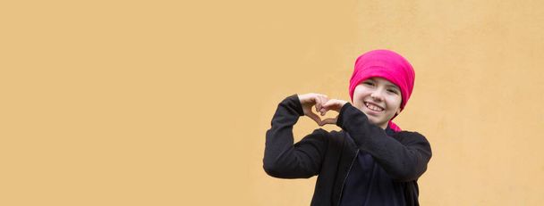 portrait of smiling girl with headscarf and making heart symbol with hands - Фото, изображение