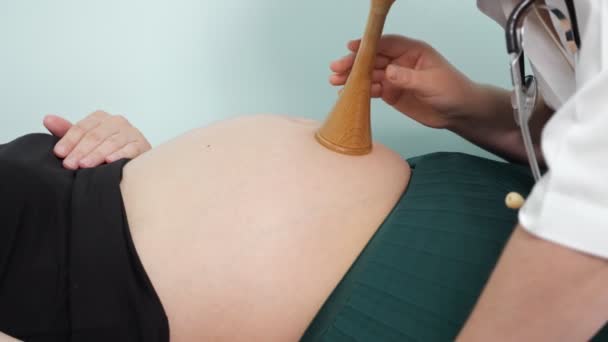 Γυναικολόγος ακούει έγκυο γυναίκα με εμβρυοσκόπιο στην κλινική - Πλάνα, βίντεο