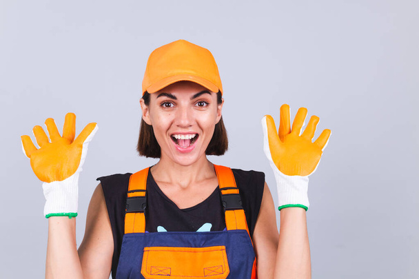 Живописець-робоча жінка в комбінезоні і рукавичках на сірому фоні щаслива позитивна посмішка весела
 - Фото, зображення