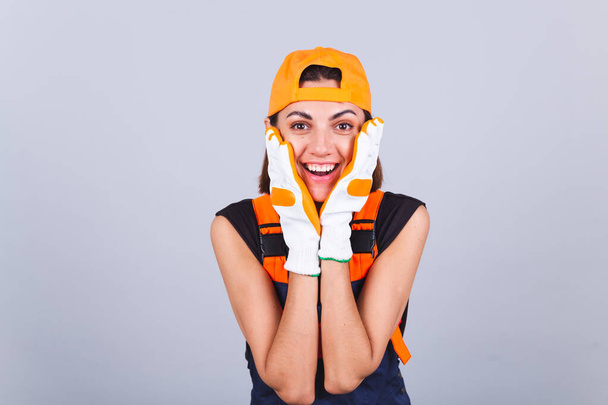 Schilder werknemer vrouw in overalls en handschoenen op grijze achtergrond gelukkig positieve glimlach vrolijk - Foto, afbeelding