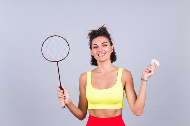 Spor giysili ve taytlı formalı kadın badminton raketini tutuyor. Mutlu, pozitif, neşeli. - Fotoğraf, Görsel