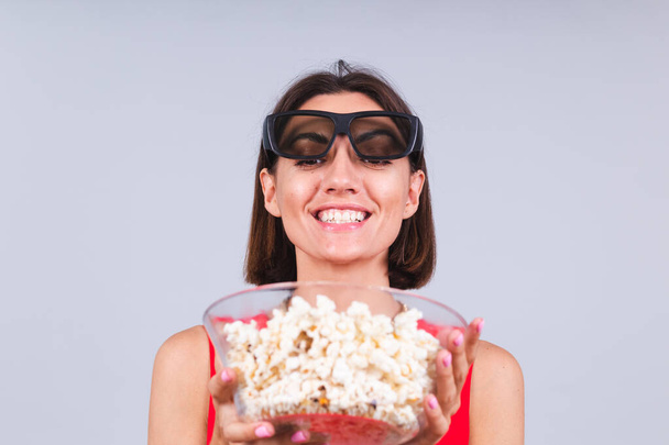 Beautiful woman on gray background in 3d cinema glasses with popcorn, cheerful happy positive emotions - Фото, зображення