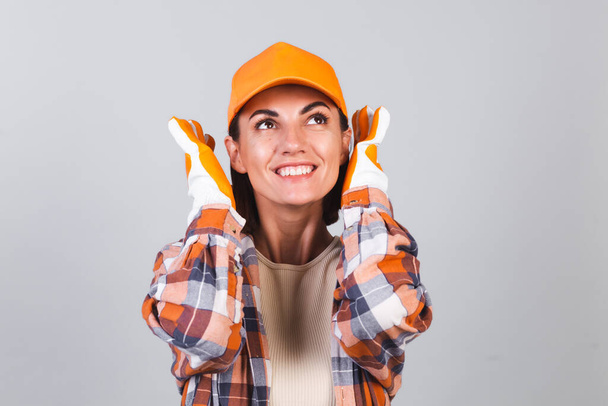 Kaunis nainen ruudullinen paita, hattu ja käsineet harmaalla taustalla onnellinen innoissaan iloinen iloinen valmis korjaus talo - Valokuva, kuva
