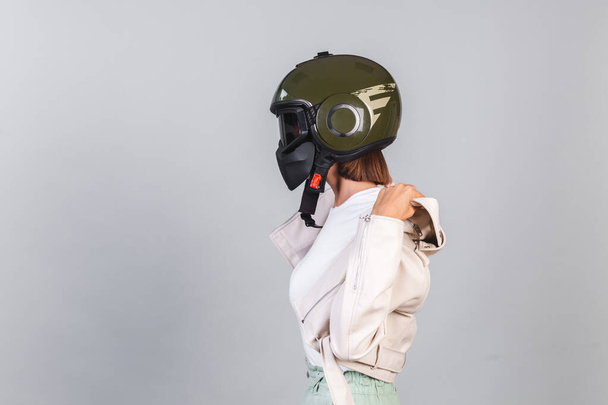 Женщина в кожаной куртке и шлеме на сером фоне - Фото, изображение