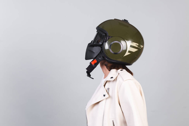 Woman in leather jacket and helmet on gray background - Photo, Image
