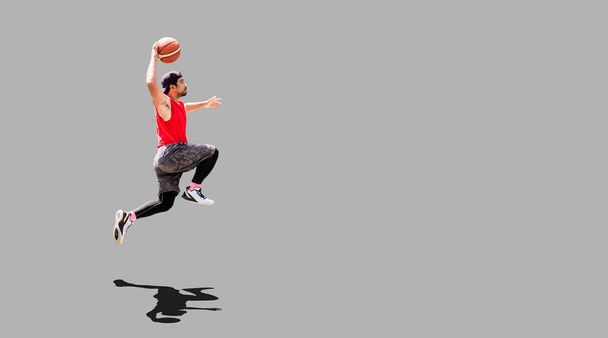 Азиатский баскетболист прыгает с трамплина, чтобы забить на цветном фоне с клиппингом - Фото, изображение