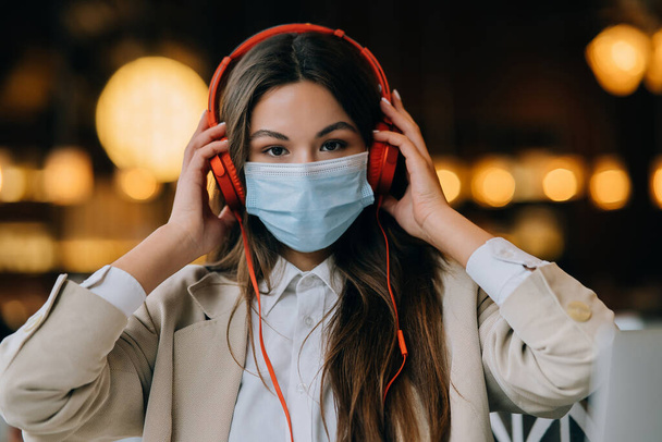 A girl sitting in a coffee shop with headphones. Coronavirus outbreak. - Foto, Imagem