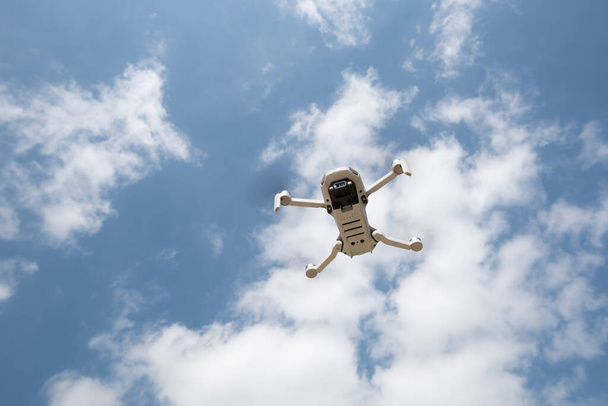 Dron z kamerą lecącą nad błękitnym, pochmurnym niebem. Fotografia krajobrazu z powietrza. - Zdjęcie, obraz