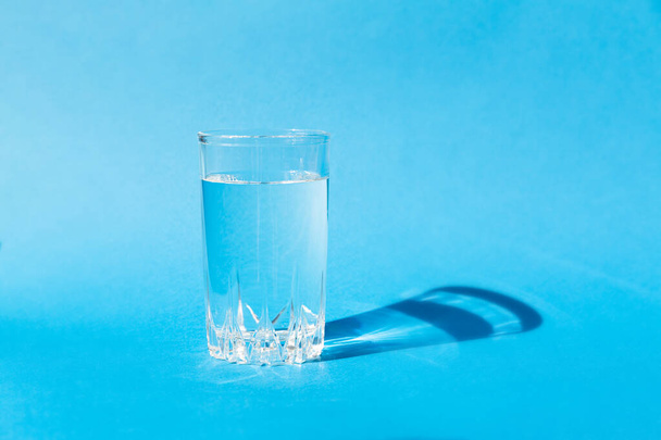 Eau fraîche et propre dans un verre sur fond bleu - Photo, image