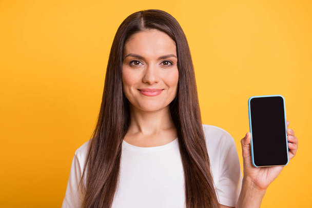 Foto ritratto di bella donna dimostrando display del telefono cellulare con spazio vuoto sorridente isolato su sfondo di colore giallo vivace - Foto, immagini