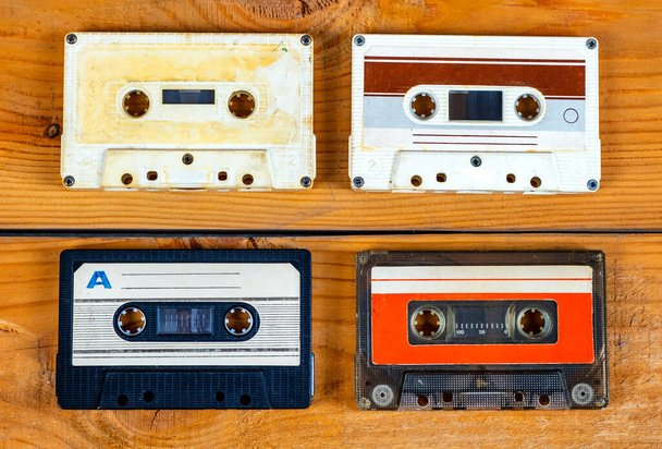 Four Old Audio Cassettes on a Wooden Planks Background closeup - Foto, Bild