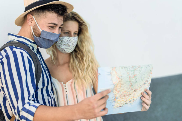 Reizen jong paar met stadsplattegrond tijdens een reis terwijl het dragen van gezichtsmasker voor het voorkomen van corona virus - Foto, afbeelding