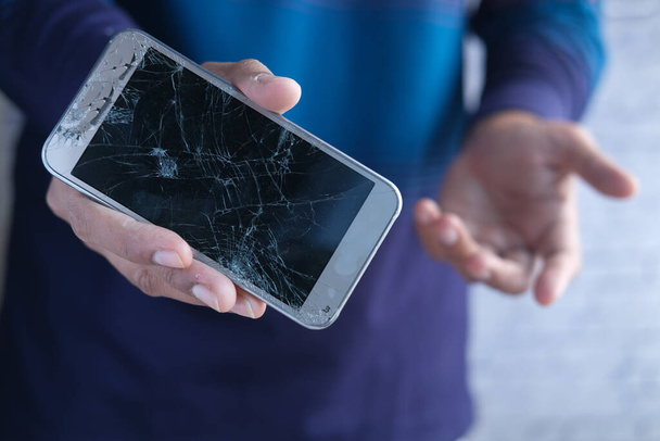 Close up of man hand holding broken smart phone. - Фото, изображение