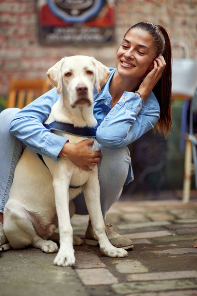 portrait of a beautiful young woman hugging and looking at her dog, smiling - Φωτογραφία, εικόνα