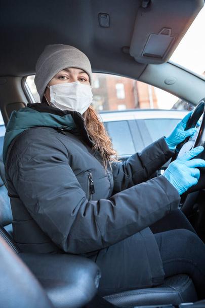 Adult woman driving to work wearing face mask and surgical blue gloves dring covid-19 epidemic, looking at camera - Фото, зображення