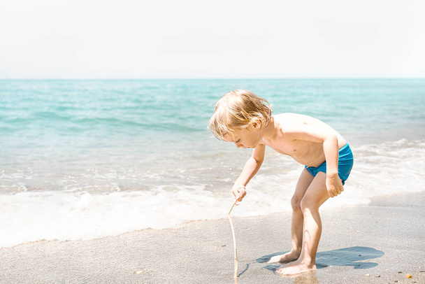 Petit garçon drôle mignon jouant avec le sable au bord de la mer. Vacances d'été à la plage, mode de vie enfant, voyage vacances - Photo, image