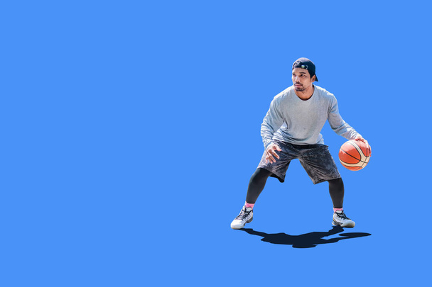 Азіатський чоловік грає в баскетбол у вільний одяг на кольоровому тлі з обрізаною стежкою. - Фото, зображення