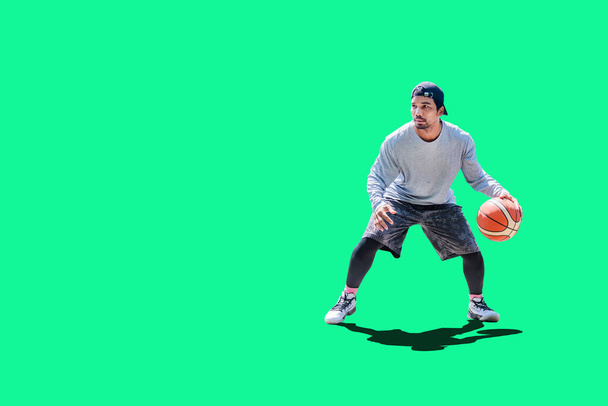 Азиатский мужчина играет в баскетбол в досуговой одежде на цветном фоне с вырезкой пути - Фото, изображение