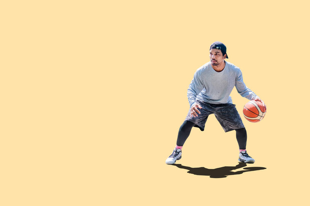 Азіатський чоловік грає в баскетбол у вільний одяг на кольоровому тлі з обрізаною стежкою. - Фото, зображення