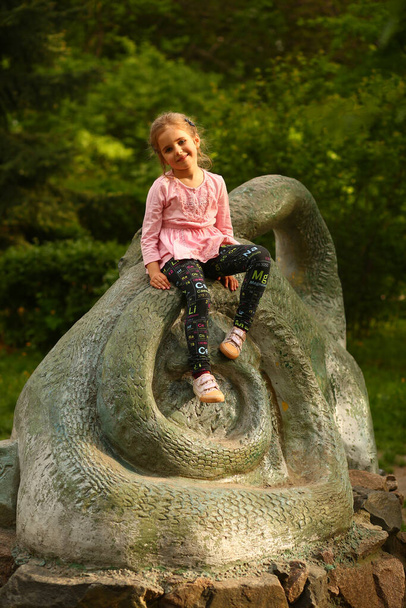Portrait of a five year old girl sitting on a rock on the playground - Photo, Image