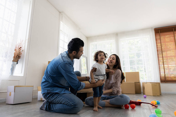 Happy family in living room. Cute daughter with parent. Moving new house a lot of parcel box. Father mother and daughter relax together at home in the morning. - Photo, Image