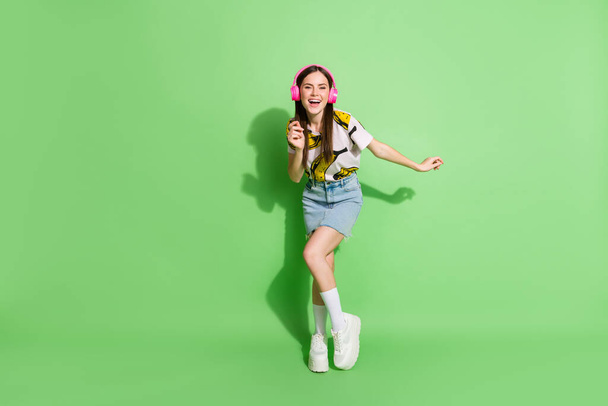 Full length photo of happy cheerful young woman dance good mood wear headphones isolated on green color background - Foto, immagini