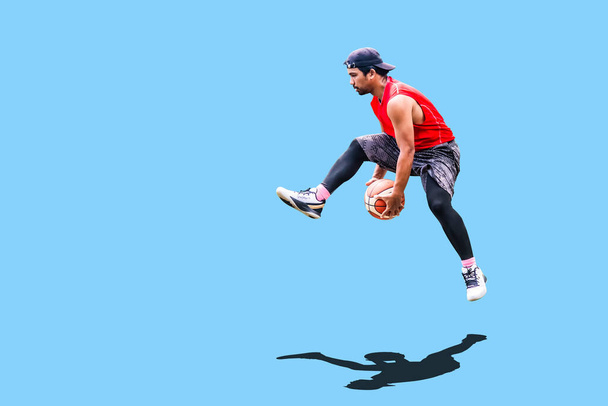 アジア人男性遊びバスケットボールでレジャー服上の色の背景 - 写真・画像