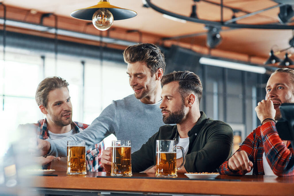 Group of young men in casual clothing enjoying beer and communicating - Photo, Image