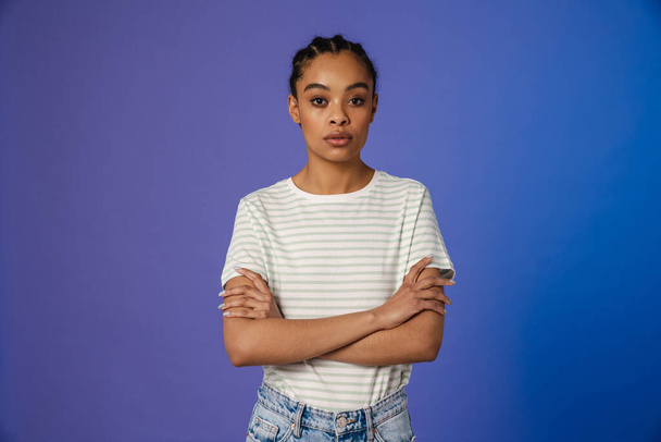 Young black woman in t-shirt posing and looking at camera isolated over blue background - Φωτογραφία, εικόνα