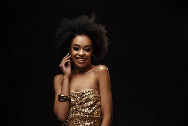 Happy african american woman in party dress smiling at camera isolated over black background - Foto, imagen
