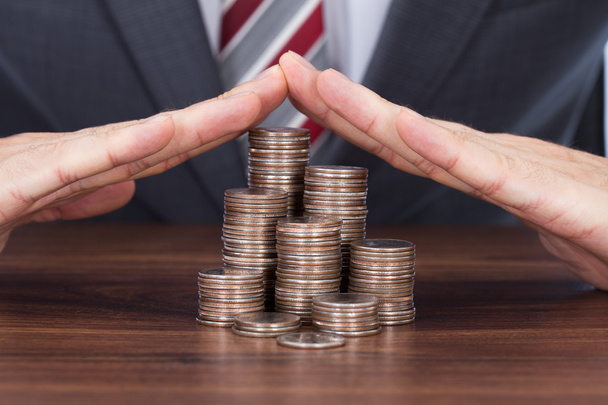 Businessman Sheltering Coin Stacks - Photo, Image