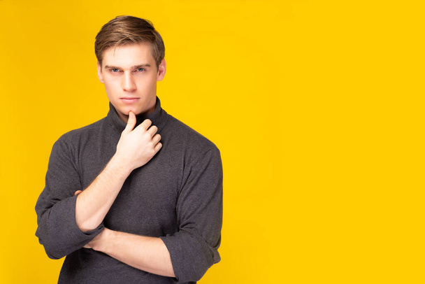 Portrait attractive self assured with confident and cool hairdo style Handsome guy wear winter clothes Young men standing over yellow background copy space He looking at camera Cool man wear sweater - Photo, Image