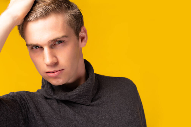 Portrait young handsome caucasian man posing with hand sleek hair Studio shot isolated on yellow background Attractive handsome guy get confident and look charming Fashion and hairstyle concept - Valokuva, kuva