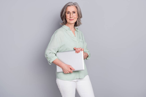 Photo of happy good looking charming mature businesswoman in glasses hold laptop isolated on grey color background - Zdjęcie, obraz