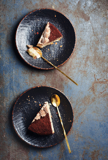 Dva kousky čokoládového dortu na černých talířích, pohled shora. - Fotografie, Obrázek