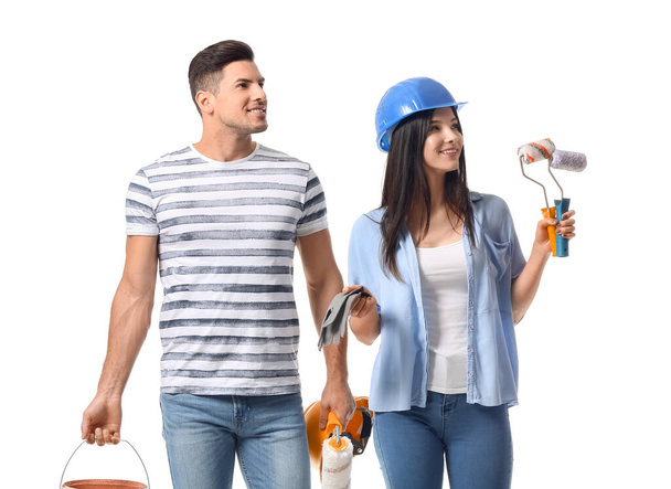 Young couple with rollers, gloves, bucket and cans of paint on white background - Photo, Image