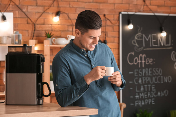 Красивый молодой человек пьет кофе в кафе - Фото, изображение