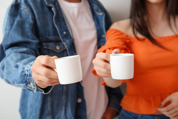 Νεαρό ζευγάρι πίνοντας καφέ στο φως φόντο, κοντινό πλάνο - Φωτογραφία, εικόνα