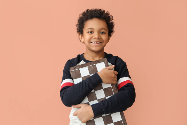 Cute African-American boy with chessboard on color background - Фото, зображення