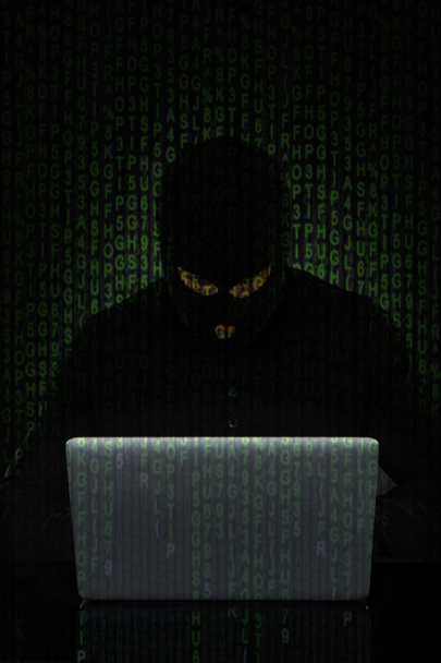 Homem vestindo Balaclava Hacking Laptop
 - Foto, Imagem
