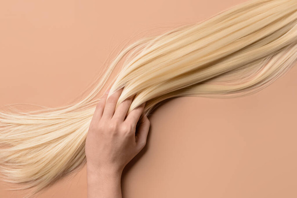 Woman with strand of blonde hair on color background - Photo, Image