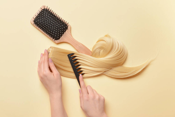 Woman with strand of blonde hair and brushes on color background - Foto, Imagem
