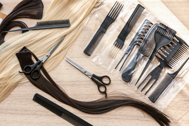 Friseurset mit Haarsträhnen und Bürsten auf hellem Holztisch - Foto, Bild